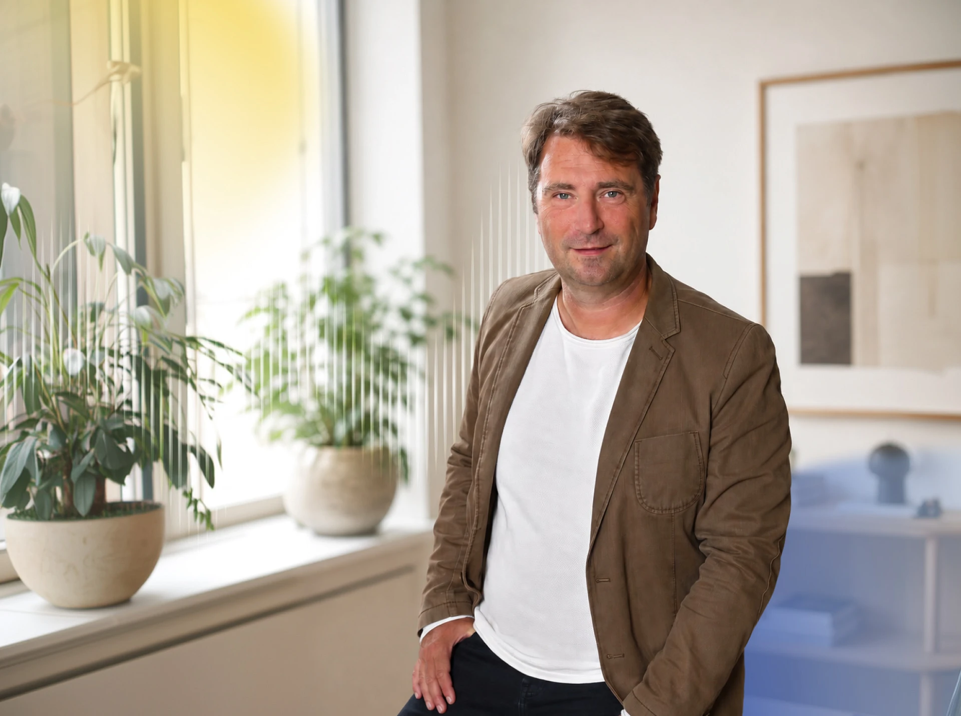 Timo Och Optimismus Coach steht im Büro und lächelt in die Kamera.